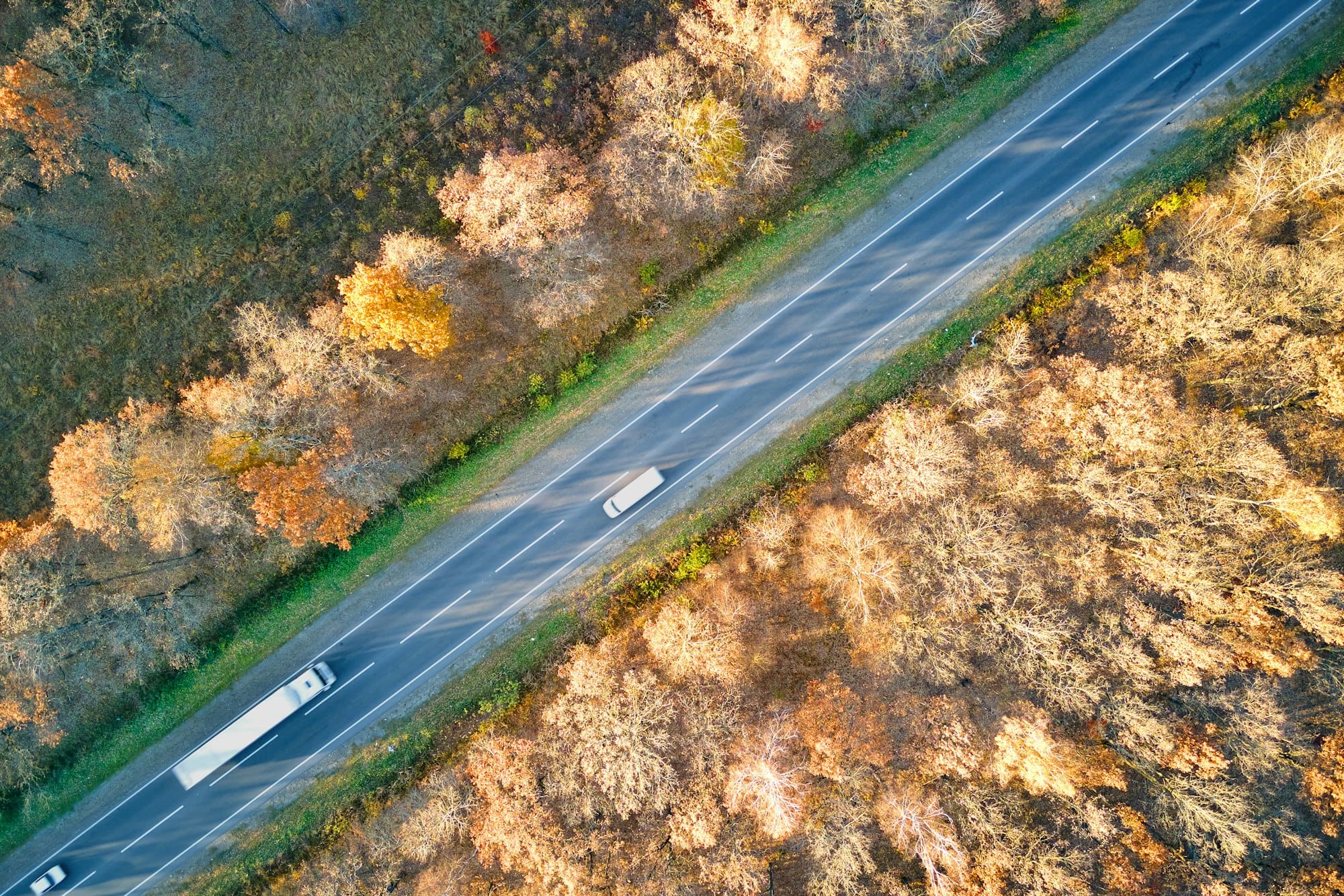 Aerial view of semi-truck with cargo trailer driving on highway hauling goods in evening